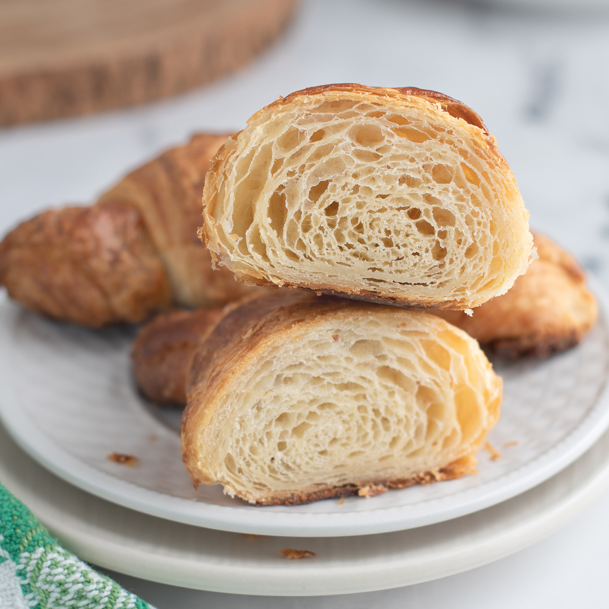 a cut sourdough croissant on a plate showing layers.