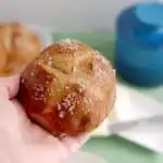 a hand holding a malt and rye pretzel rolls