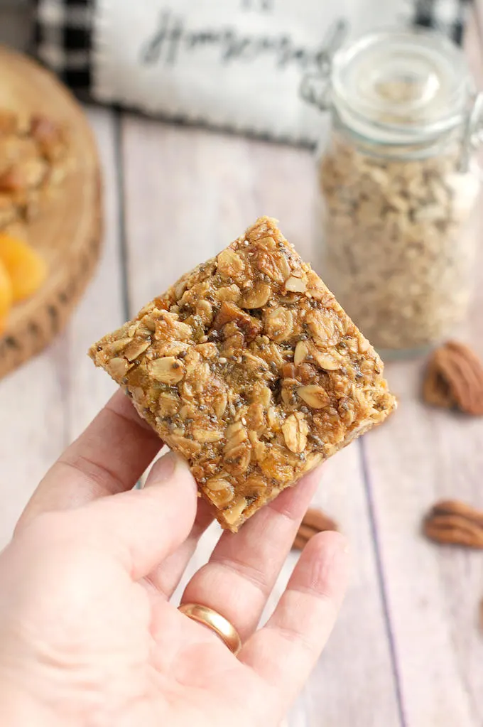 a hand holding an apricot granola bar