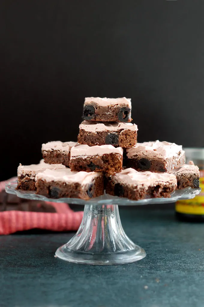 a cake stand with chocolate cherry brownies stacked on top