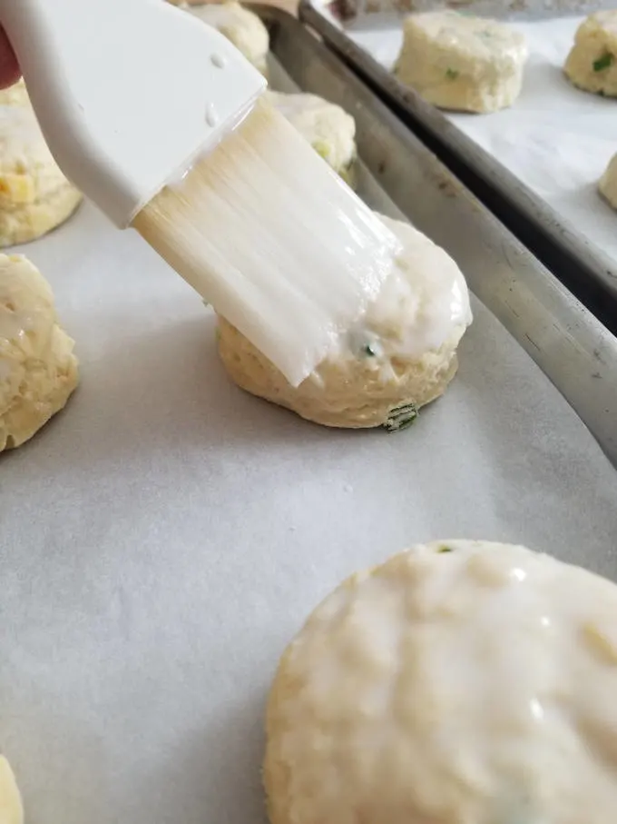 Irish Cheddar & Scallion scones being brush with buttermilk before baking.