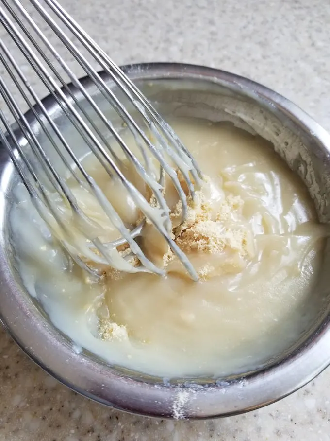 a bowl of pudding with malted milk powder being whisked in.