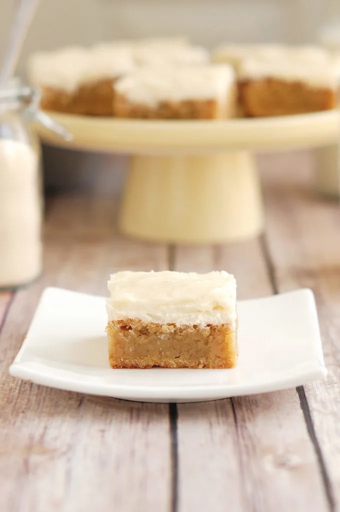 a malted milk blondie with malted milk frosting on a white plate