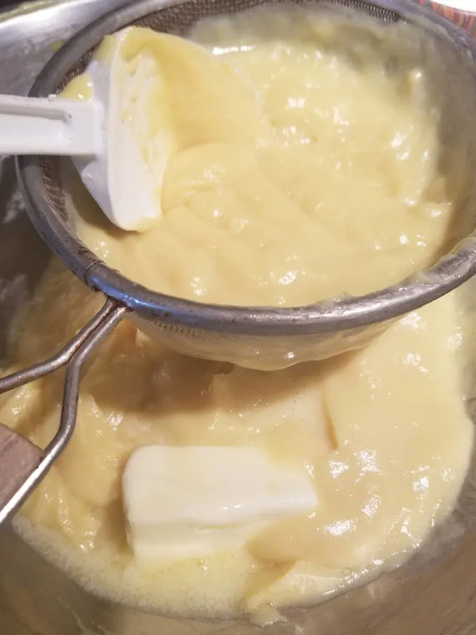 pastry cream being strained though a sieve.