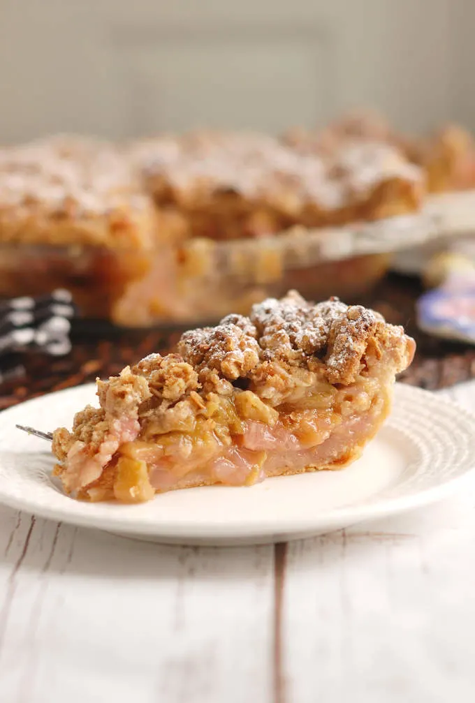 a slice of rhubarb crumb pie on a white plate.