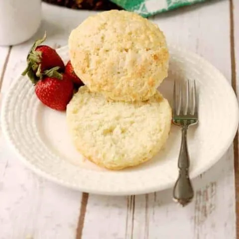 a split shortcake biscuit on a plate with strawberries