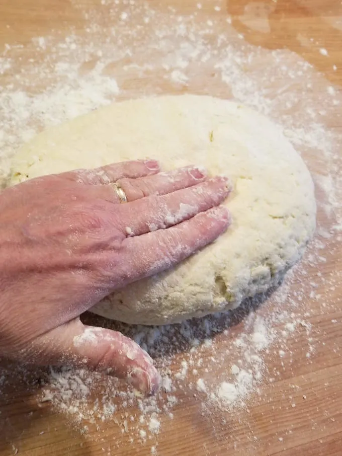 a hand patting out shortcake biscuit dough
