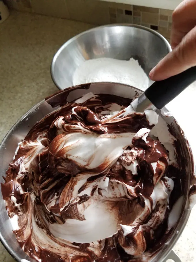 folding chocolate into a bowl of meringue