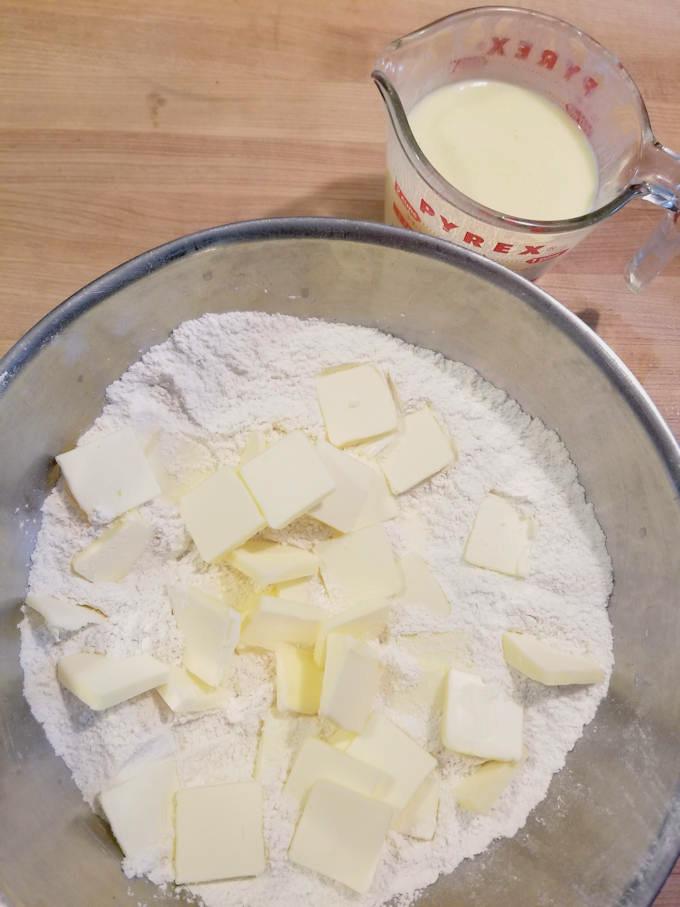 dry ingredients for shortcake biscuits in a bowl with lumps of butter on top.
