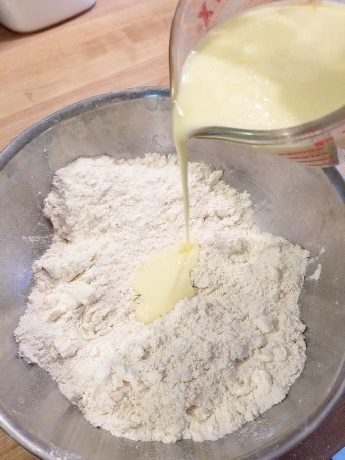 dry ingredients for shortcake biscuits in a steel bowl with milk pouring in.