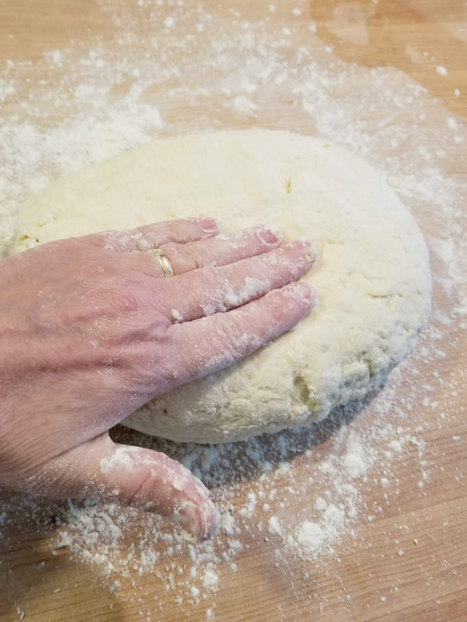 a hand patting shortcake biscuit dough flat.