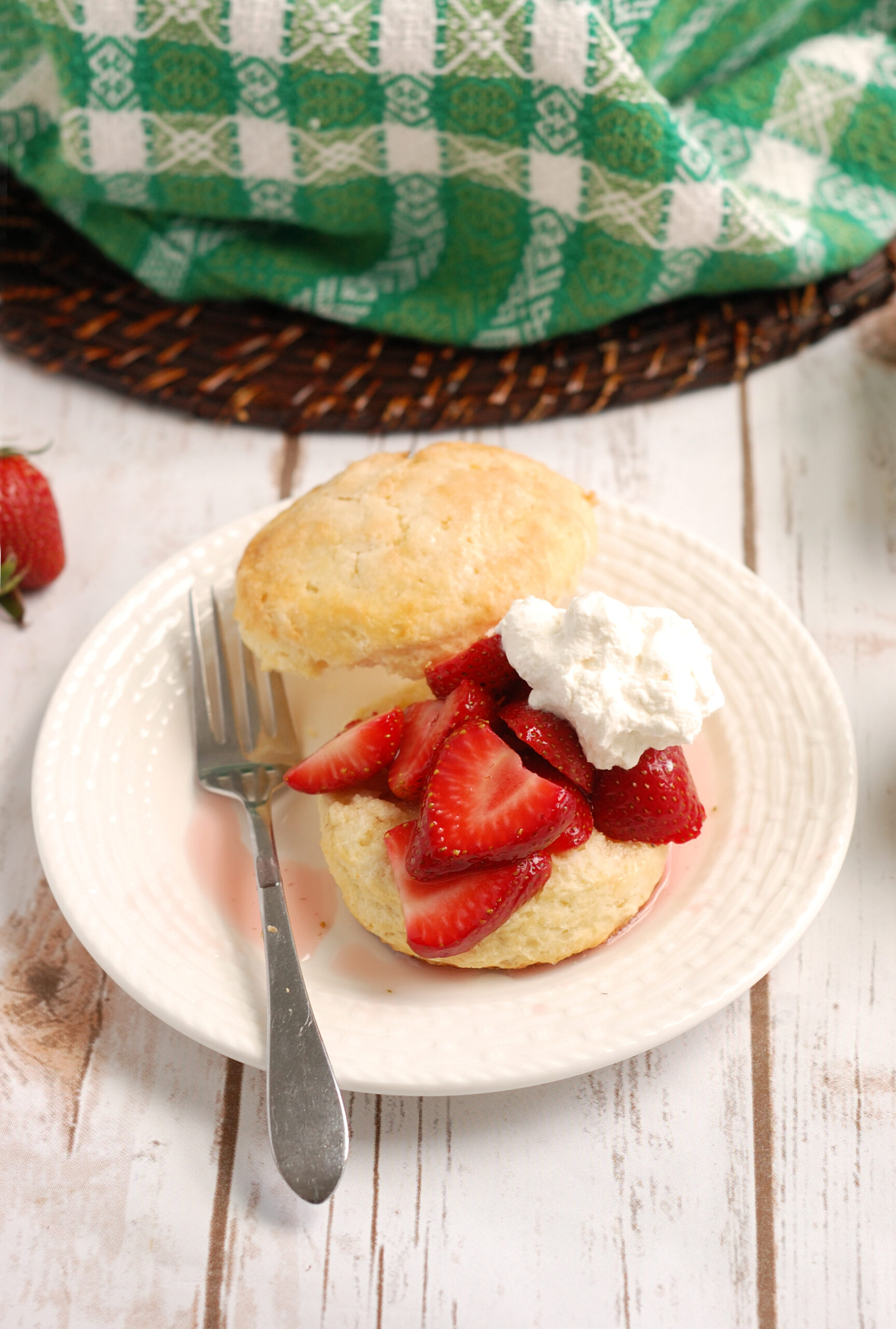 a strawberry shortcake with a fork on a white plate.