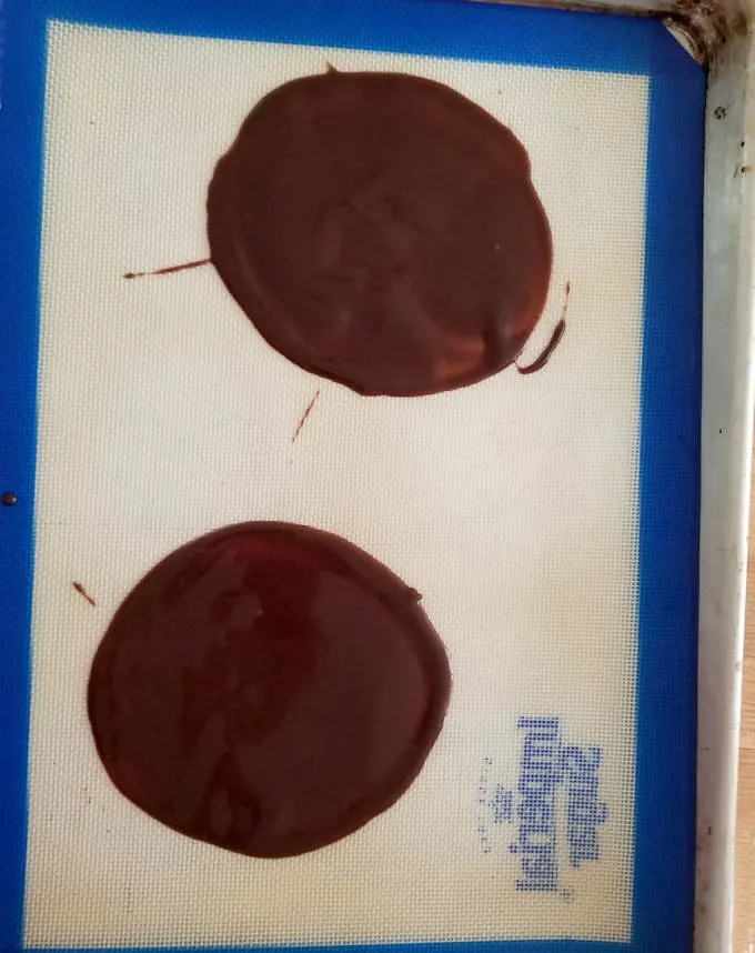 a baking tray with two chocolate cookies spread very thin