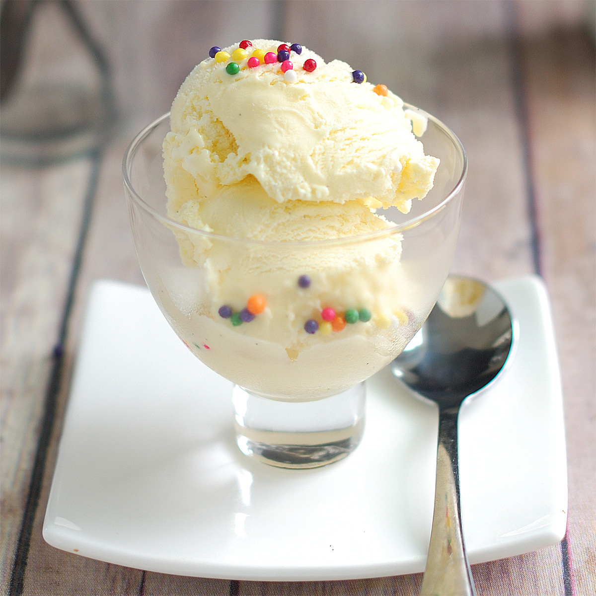 a bowl of vanilla ice cream with sprinkles on a white plate.