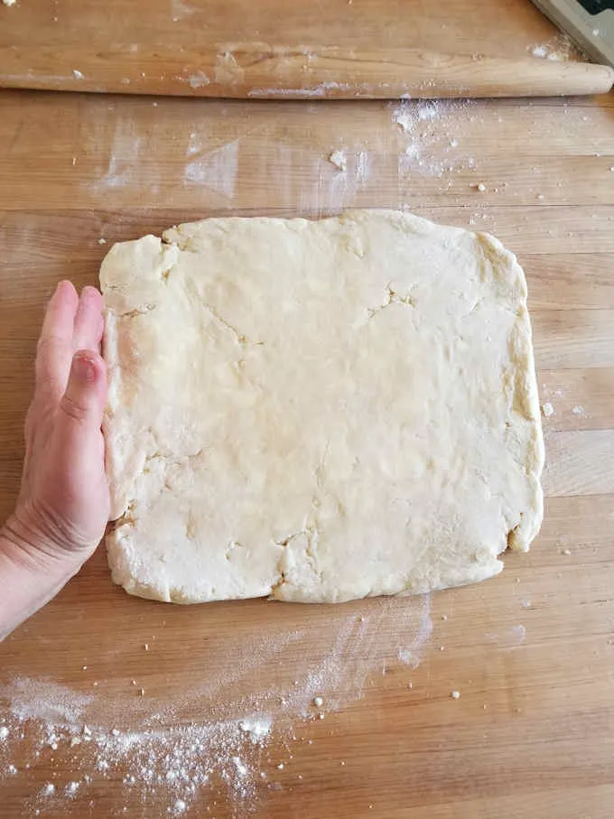 a square of pie dough on a wooden table