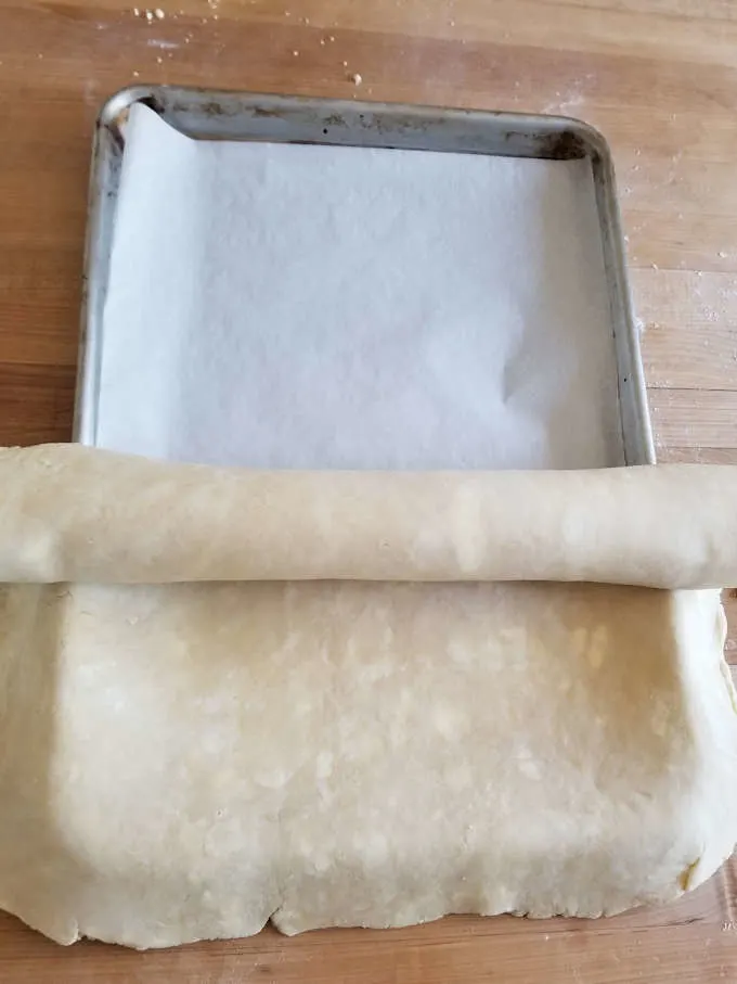 Unrolling pie dough into a pan