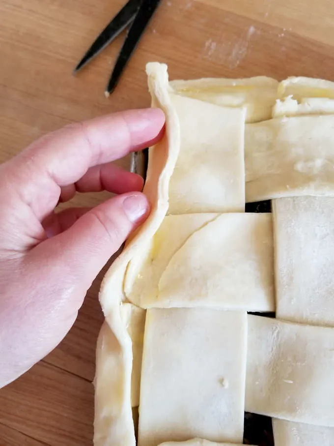a hand folding the edge of a pie crust