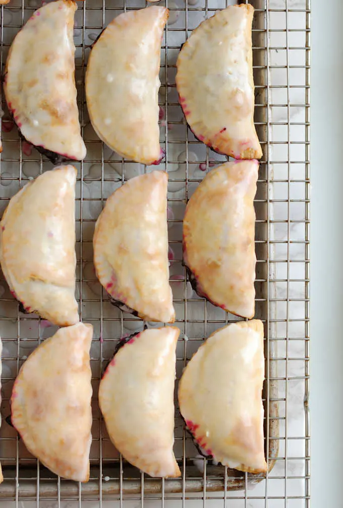 a tray of glazed blueberry hand pies cooling.