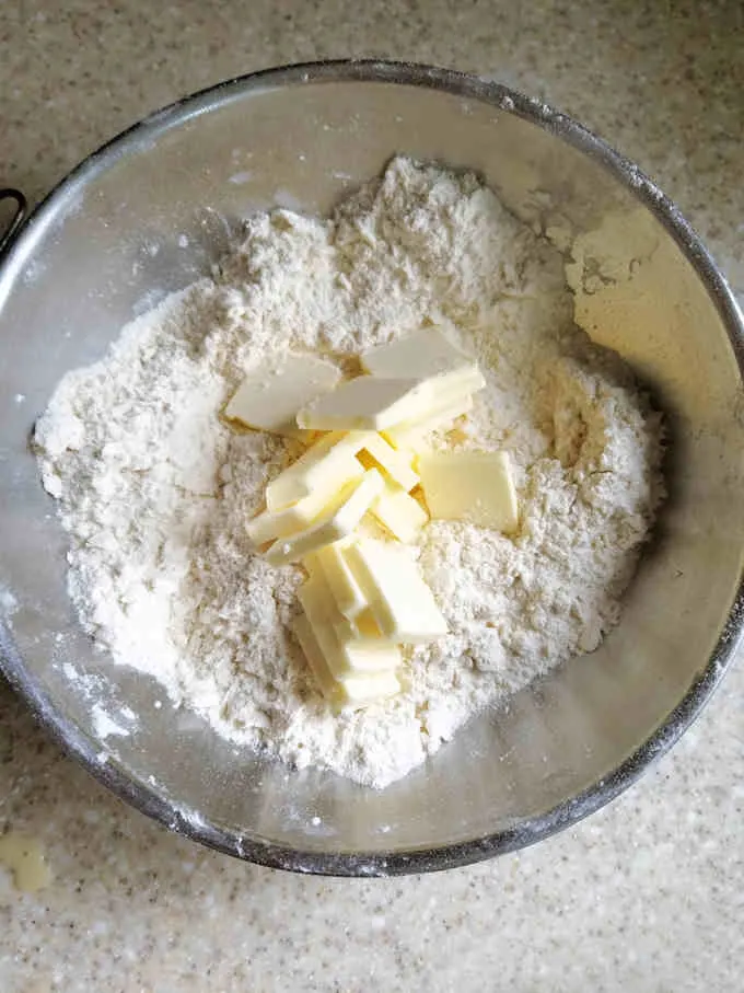 a bowl of flour with slices of butter on top
