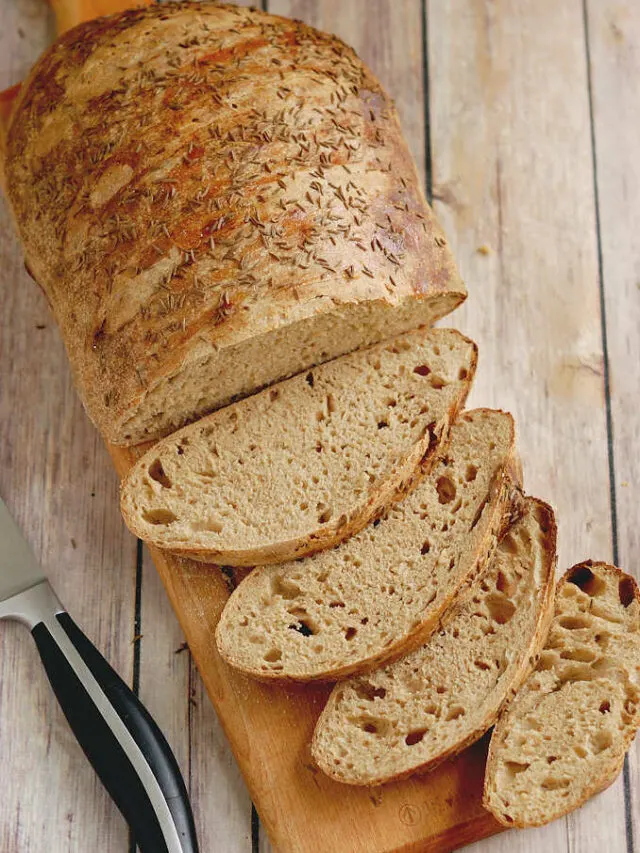 a sliced loaf of sourdough rye on a cutting board.