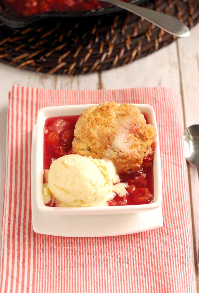 a bowl of cherry cobbler and vanilla ice cream