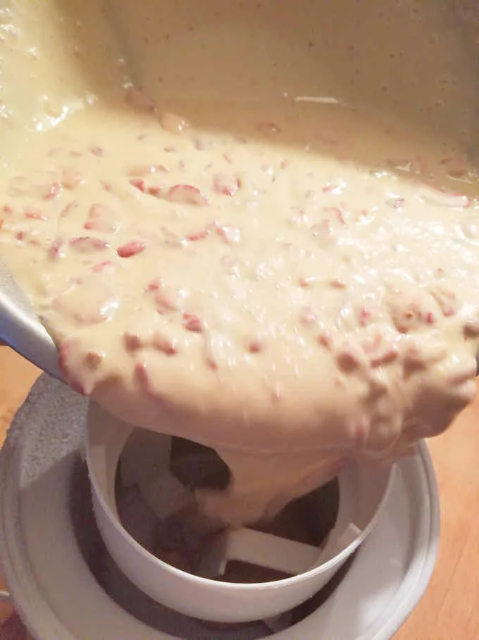 pouring strawberry ice cream into an ice cream maker.