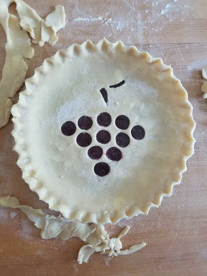 an unbaked concord grape pie on a wooden table