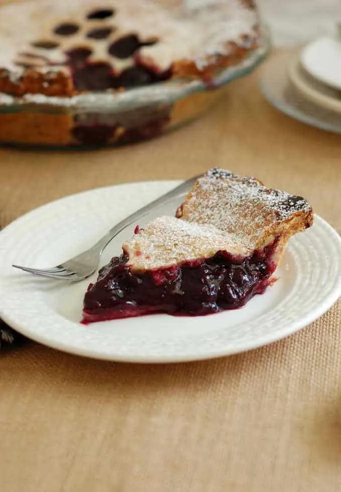 a slice of concord grape pie on a white plate with a fork