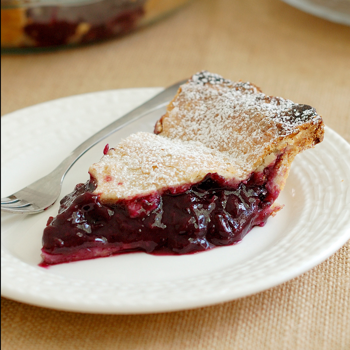 a slice of concord grape pie on a white plate.