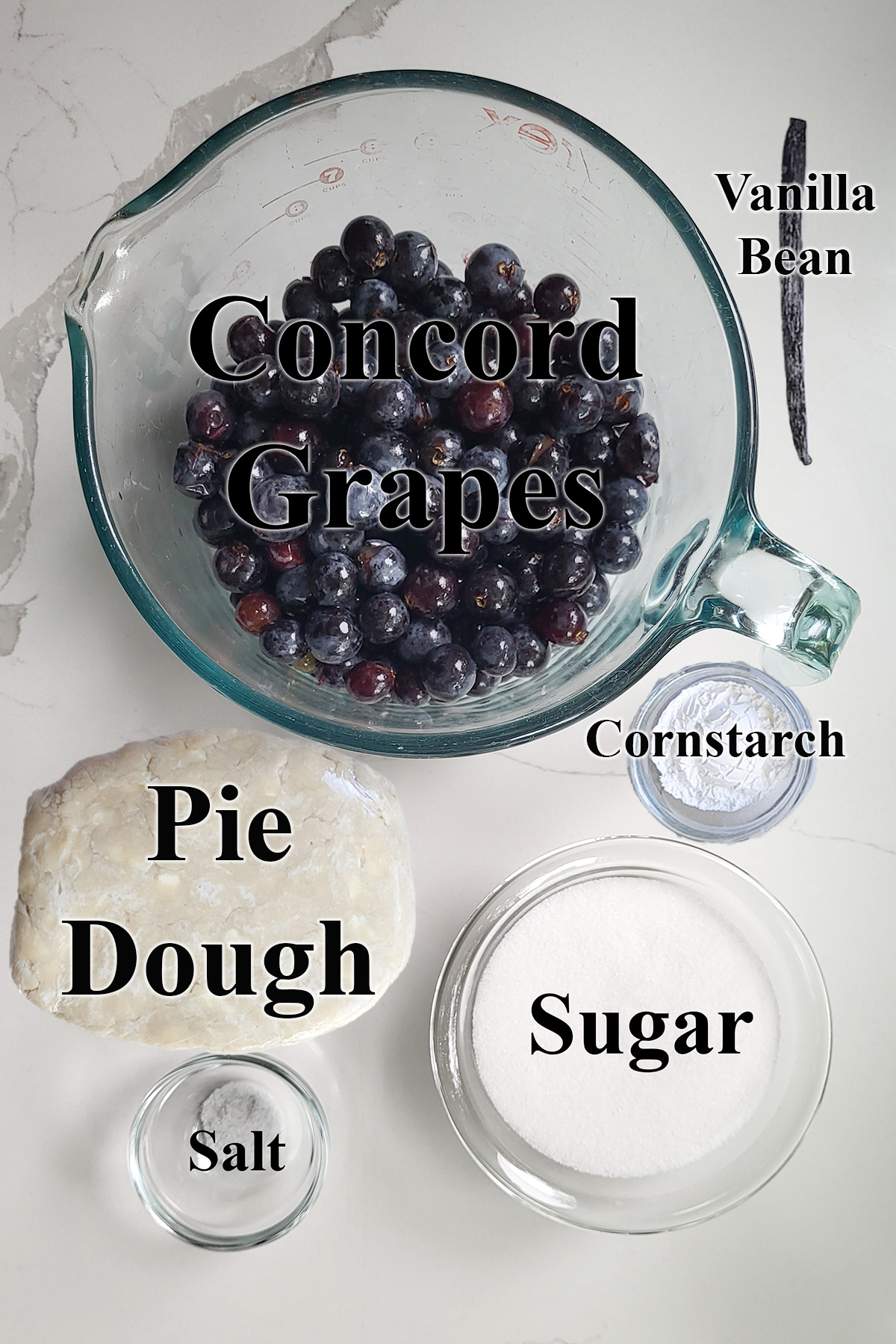 ingredients for concord grape pie in glass bowls on a white surface.