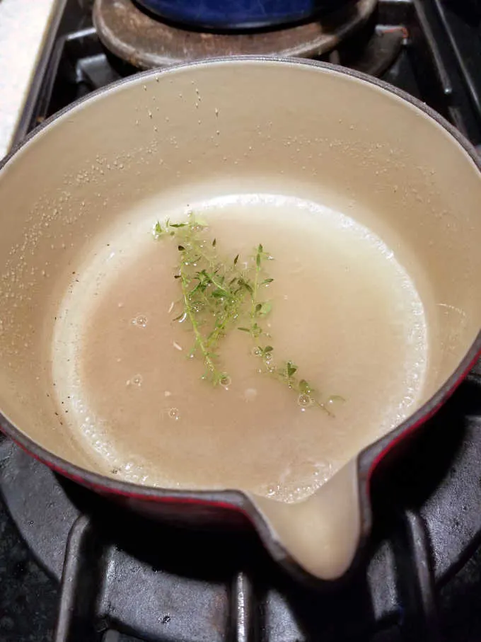 a pot on a stove filled with sugar, lemon juice and thyme leaves