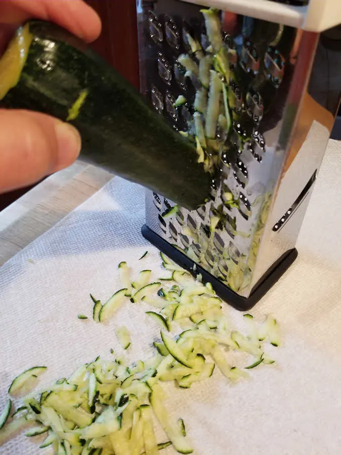 grating a zucchini on a box grater