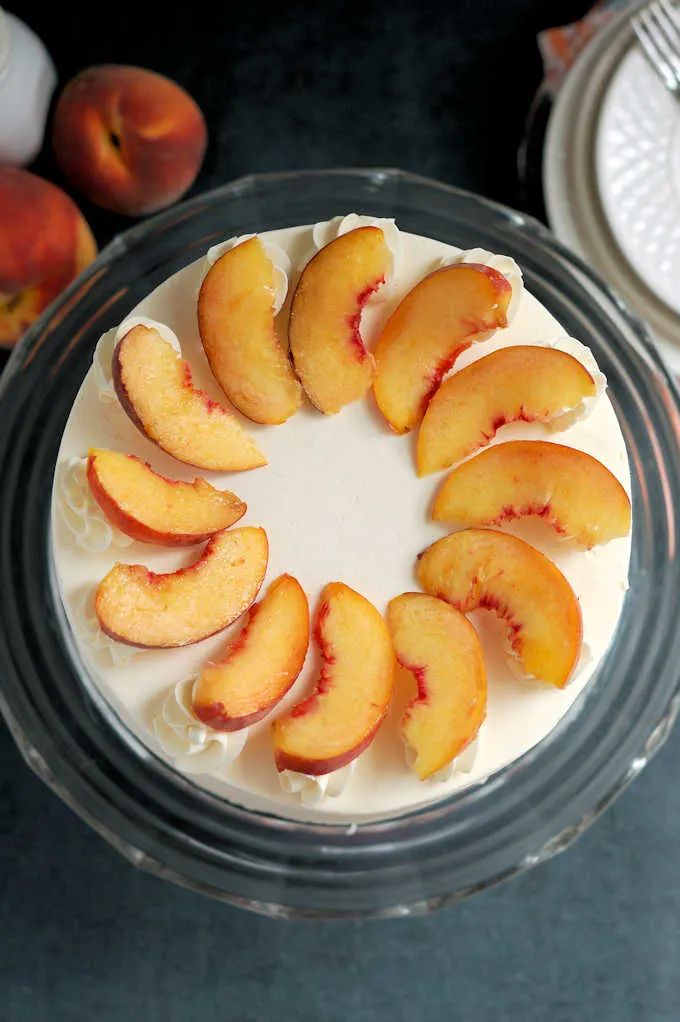 top view of a peach melba cake decorated with fresh peach slices