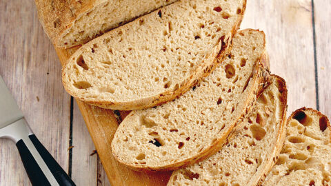 a slice loaf of rye bread on a cutting board.