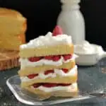 a slice of vanilla cake with raspberries and cream on a plate