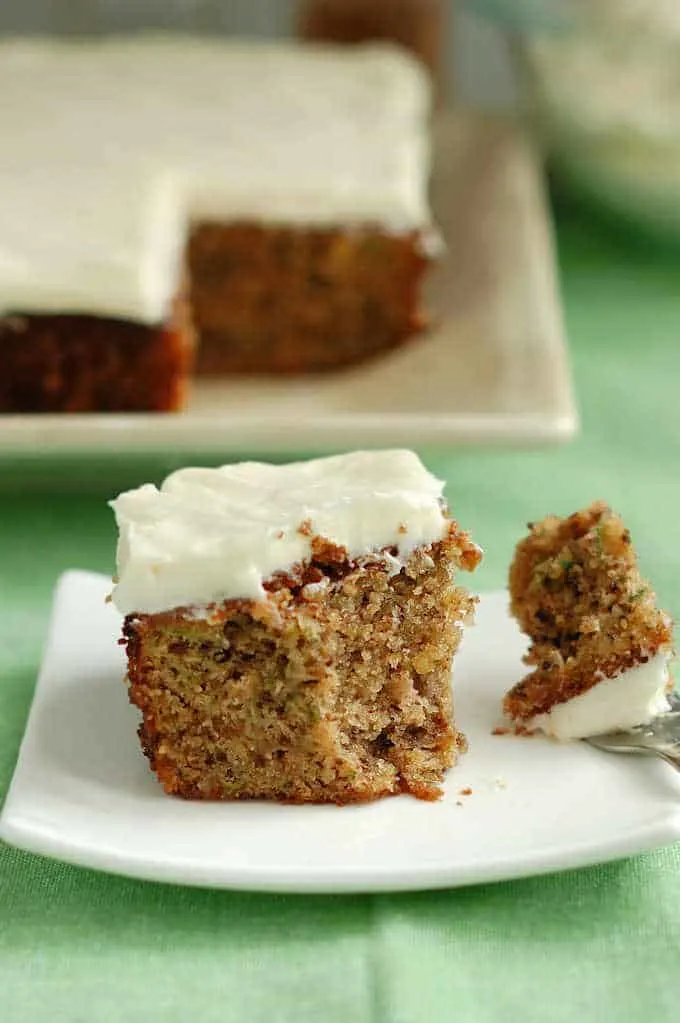 a partially eaten slice of zucchini cake on a plate with a fork