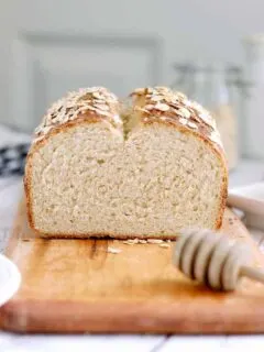 a sliced loaf of honey oatmeal bread on a cutting board