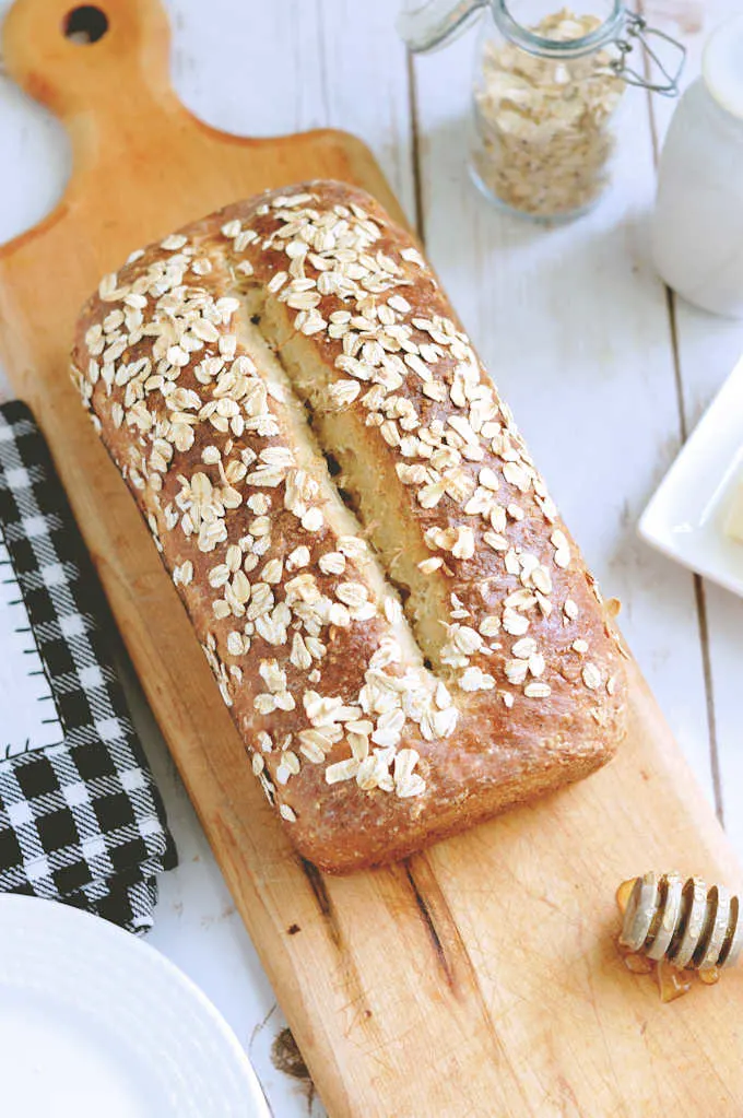 a loaf of honey oatmeal bread on a cutting board