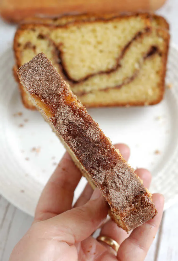 a hand holding a slice of bread showing the cinnamon crust