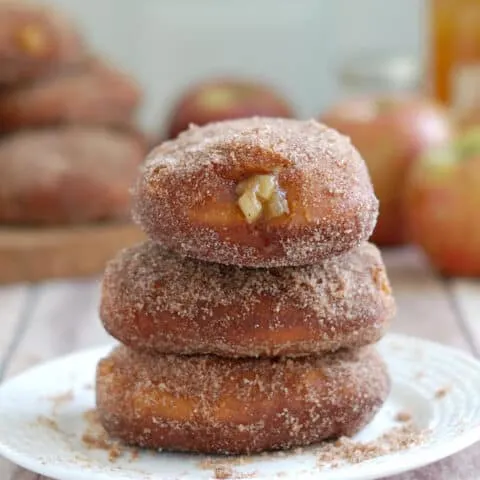 three apple filled cider donuts on a plate