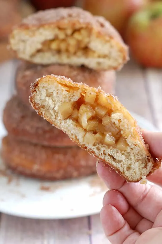 a hand holding an apple filled cider donut