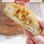 a split apple filled donut in a hand.