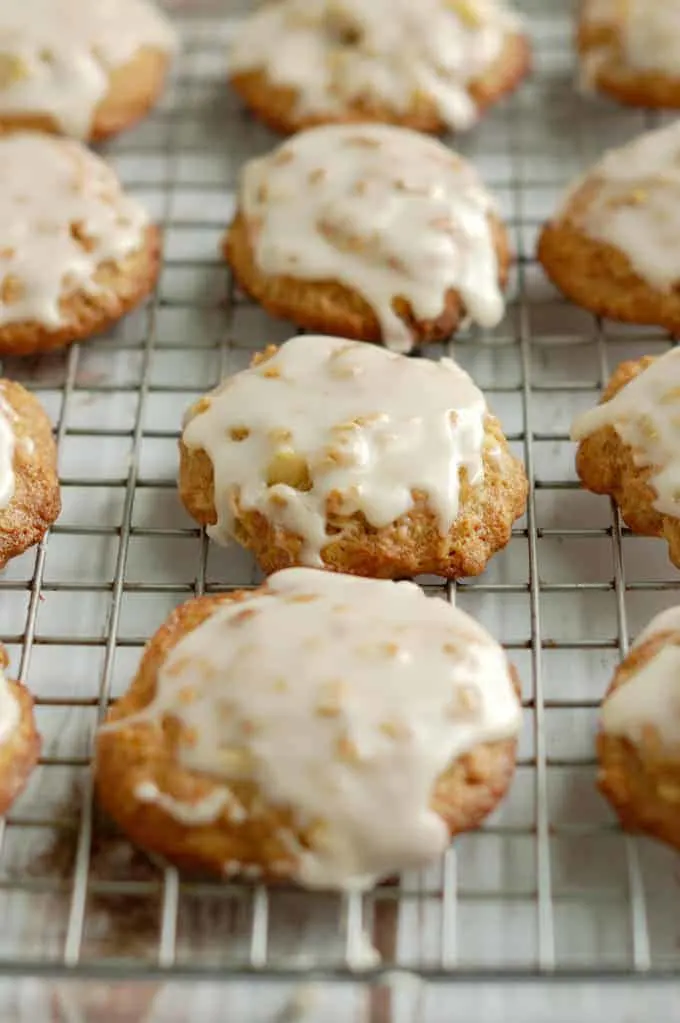 a closeup of an iced apple oatmeal cookie on a cooling rack
