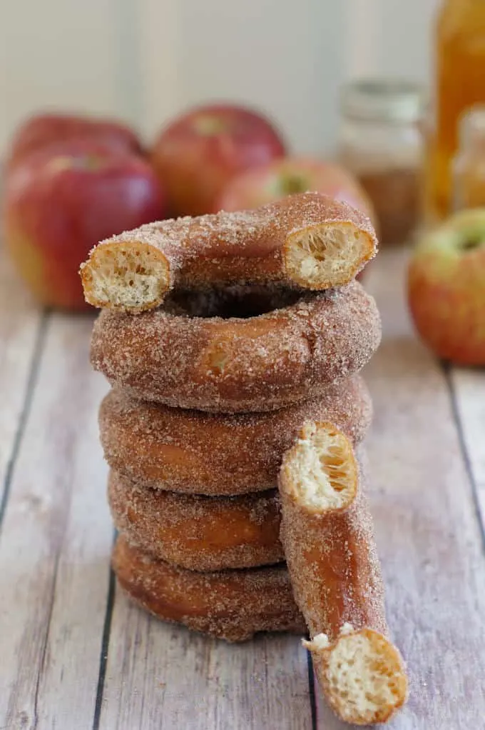 a stack of apple cider donuts with one broken to show the interior