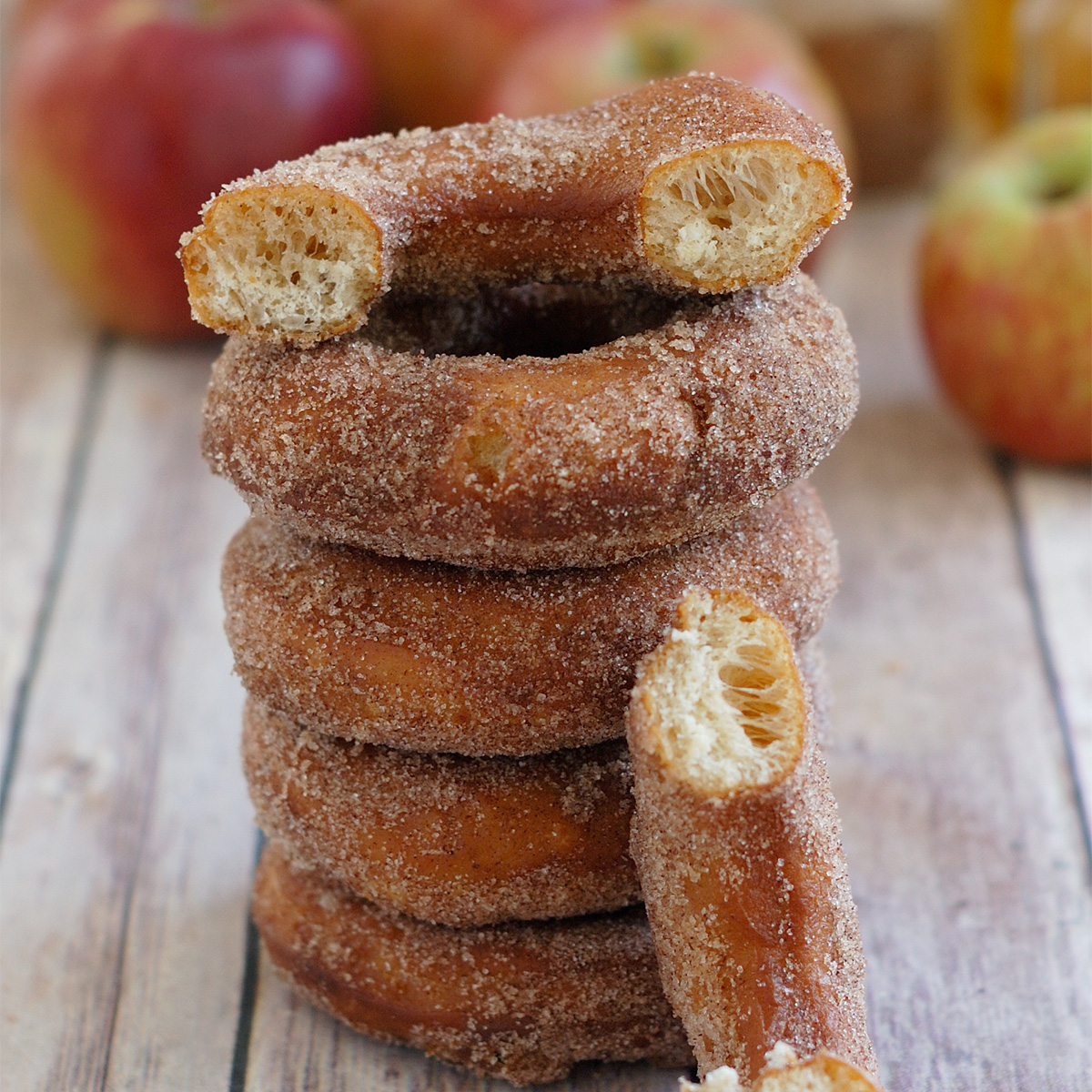 a stack of cider donuts on a wood surface.
