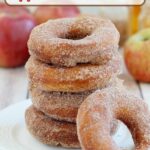 a stack of cider donuts on a white plate.
