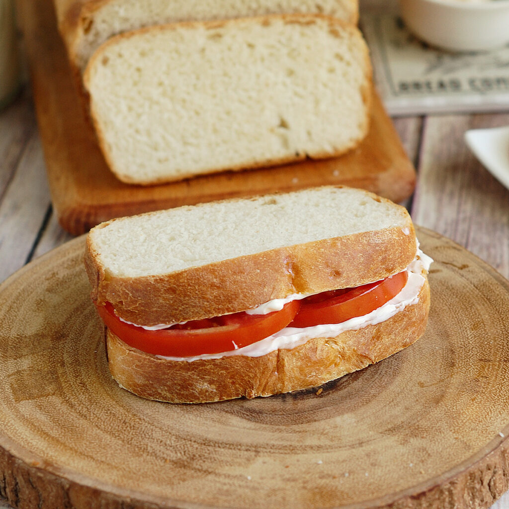 a sourdough tomato sandwich on a cutting board.