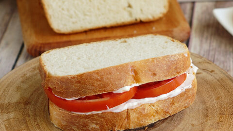 a sourdough tomato sandwich on a cutting board.