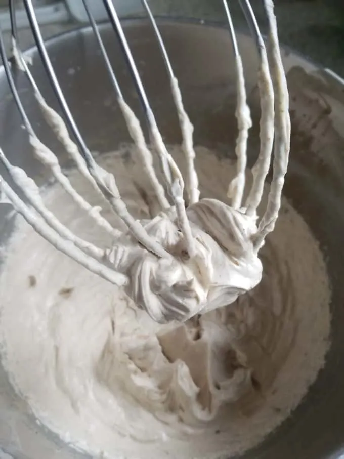 A closeup of a whisk with a dollop of whipped ganache on the end