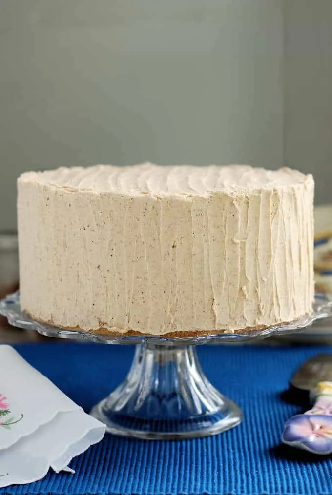 a spice cake frosted with spiced ganache on a glass cake stand